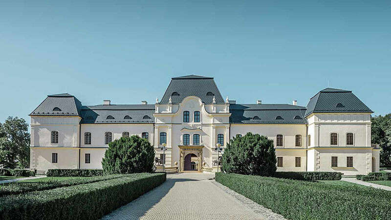 Frontale Aufnahme des Schlosses Humenne mit saniertem Dach aus Aluminium in anthrazit und Parkanlage im Vordergrund