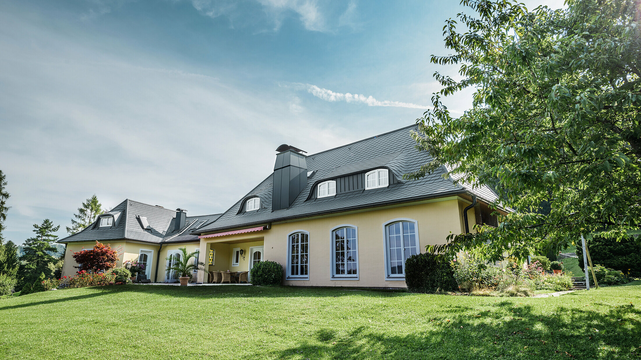 Klassisches Einfamilienhaus mit geschwungenen Gauben, eingedeckt mit der sturmsicheren PREFA Dachschindel, mit 40 Jahren Materialgarantie.