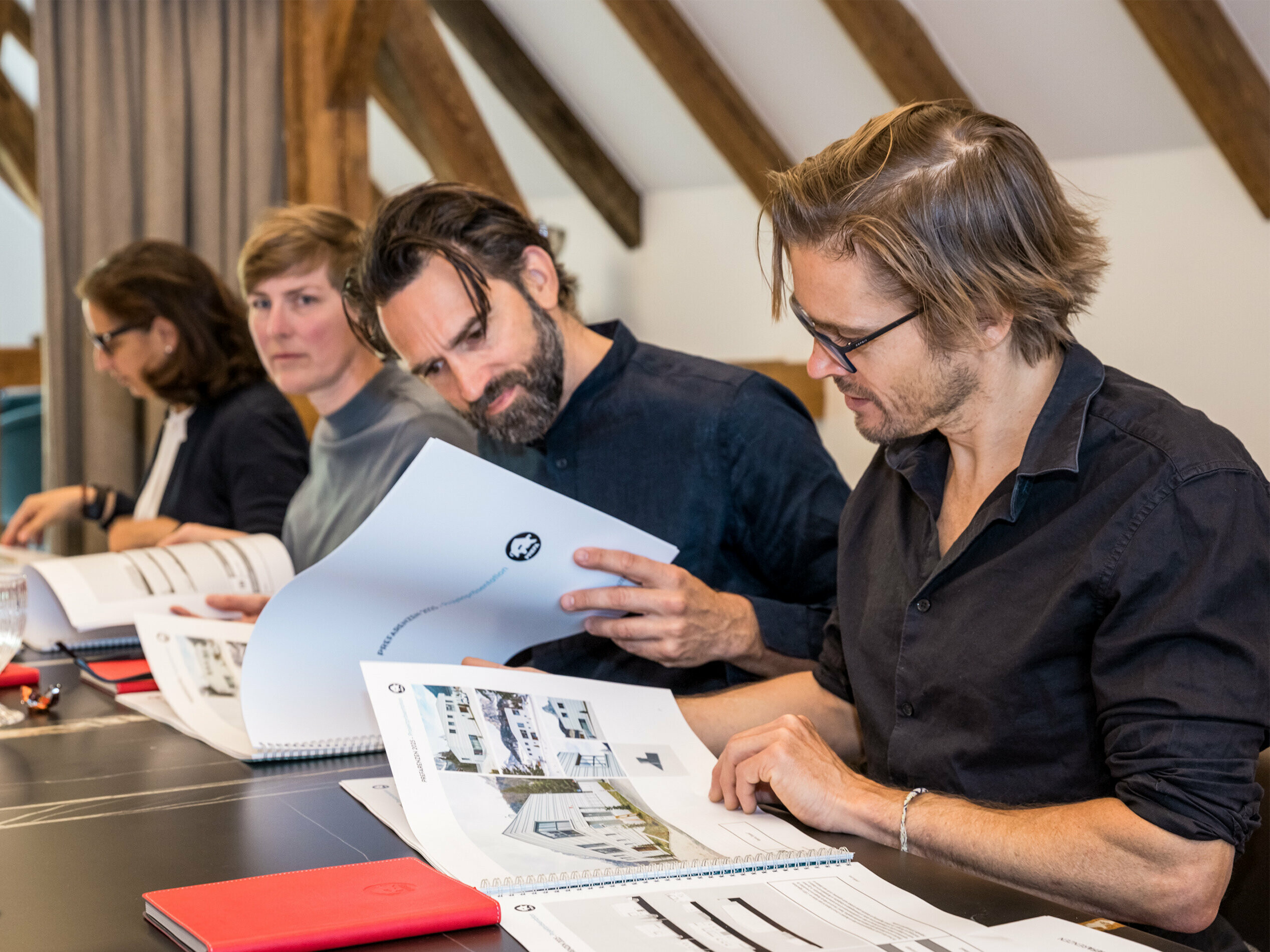 Eine Jury von Architekten bei der Durchsicht von Unterlagen für die Auswahl der PREFARENZEN 2025. Die Jurymitglieder sitzen an einem Tisch und betrachten detaillierte Projektpräsentationen.
