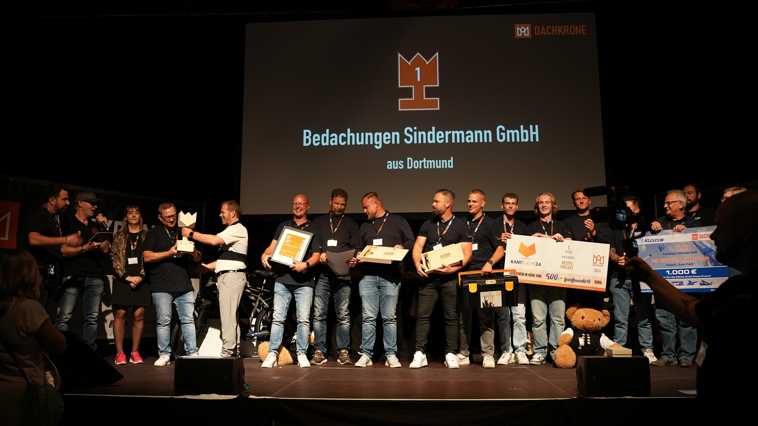 Dirk Sindermann von Bedachungen Sindermann GmbH bekommt bei der Dachkrone 2024 auf der Bühne den Preis für das beste Projekt überreicht. 