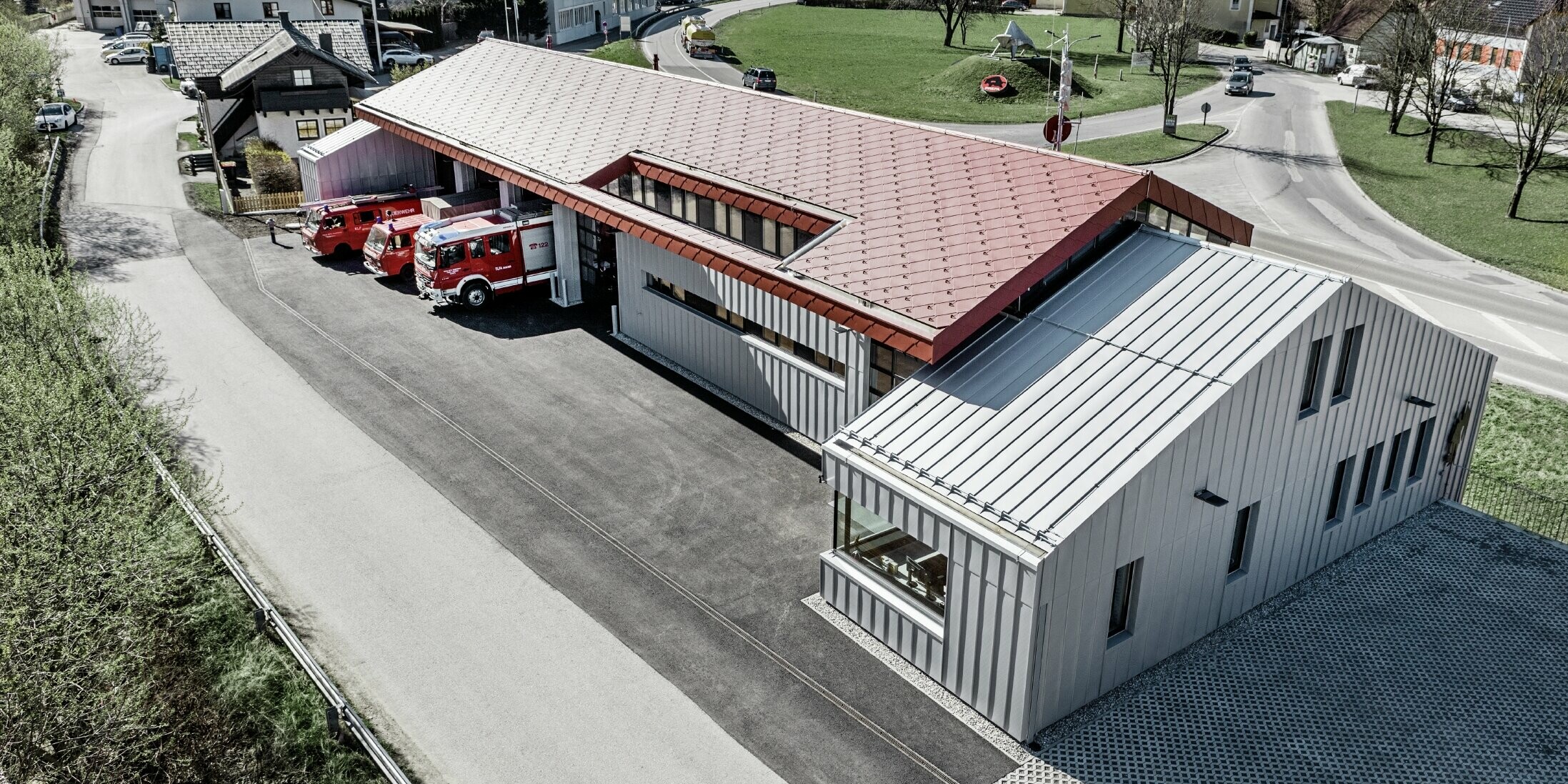 Aufnahme der Betriebsfeuerwehr in Marktl/Lilienfeld in der Vogelperspektive. Der linke Gebäudeteil wurde komplett am Dach und der Fassade mit der raute 44 in Oxydrot verkleidet. Der rechte Teil bekommt eine Aluminiumhülle mit Prefalz in Silbermetallic.