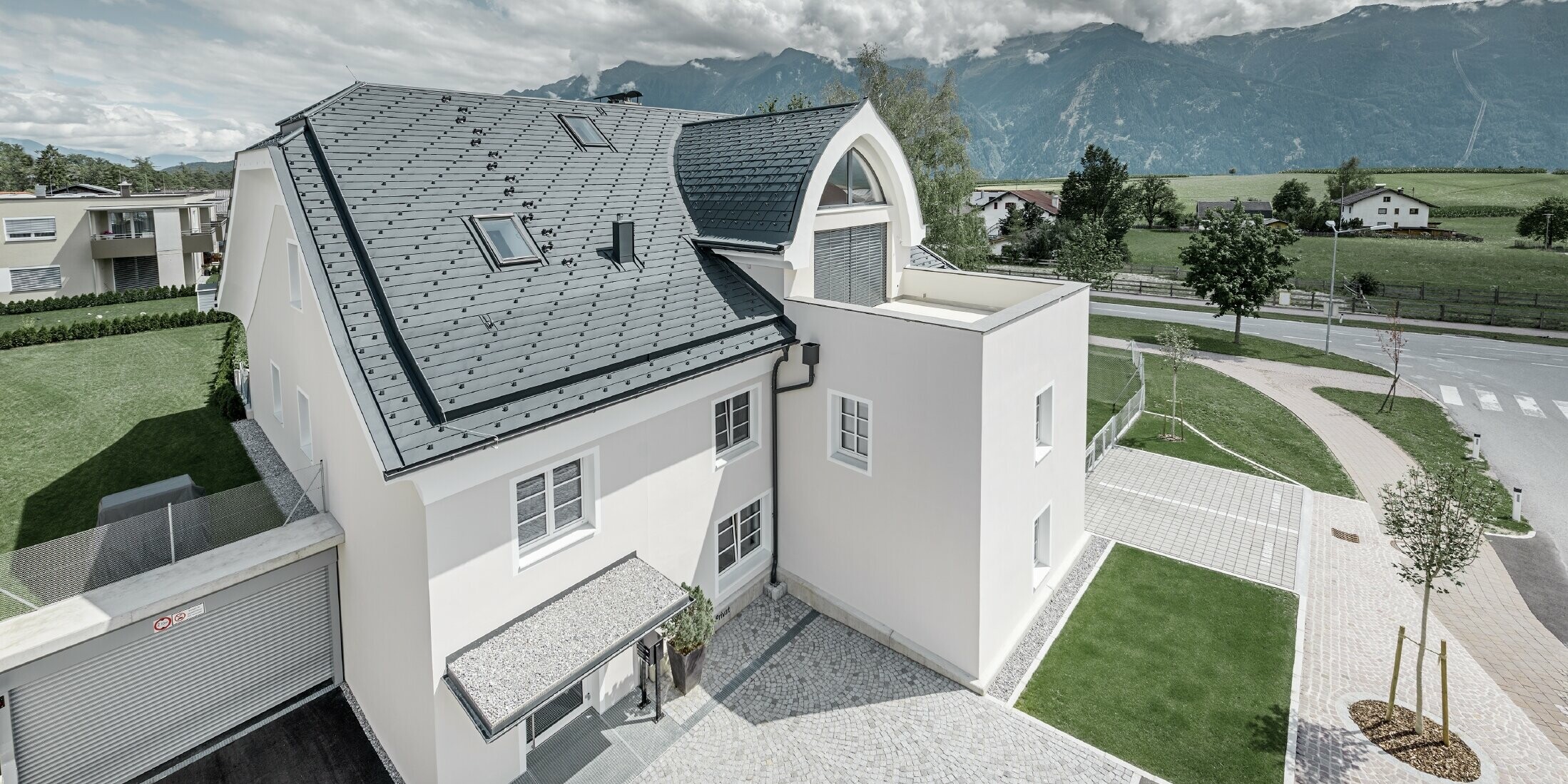 Neu saniertes Wohnhaus mit neuem PREFA Dach; Das Krüppelwalmdach mit Spitztonnengaube und Loggia wurde mit der Alu Schindel von PREFA in Anthrazit eingedeckt. Es wurden auch Schneestopper, Fenstereinfassung und Rinne von PREFA verbaut.