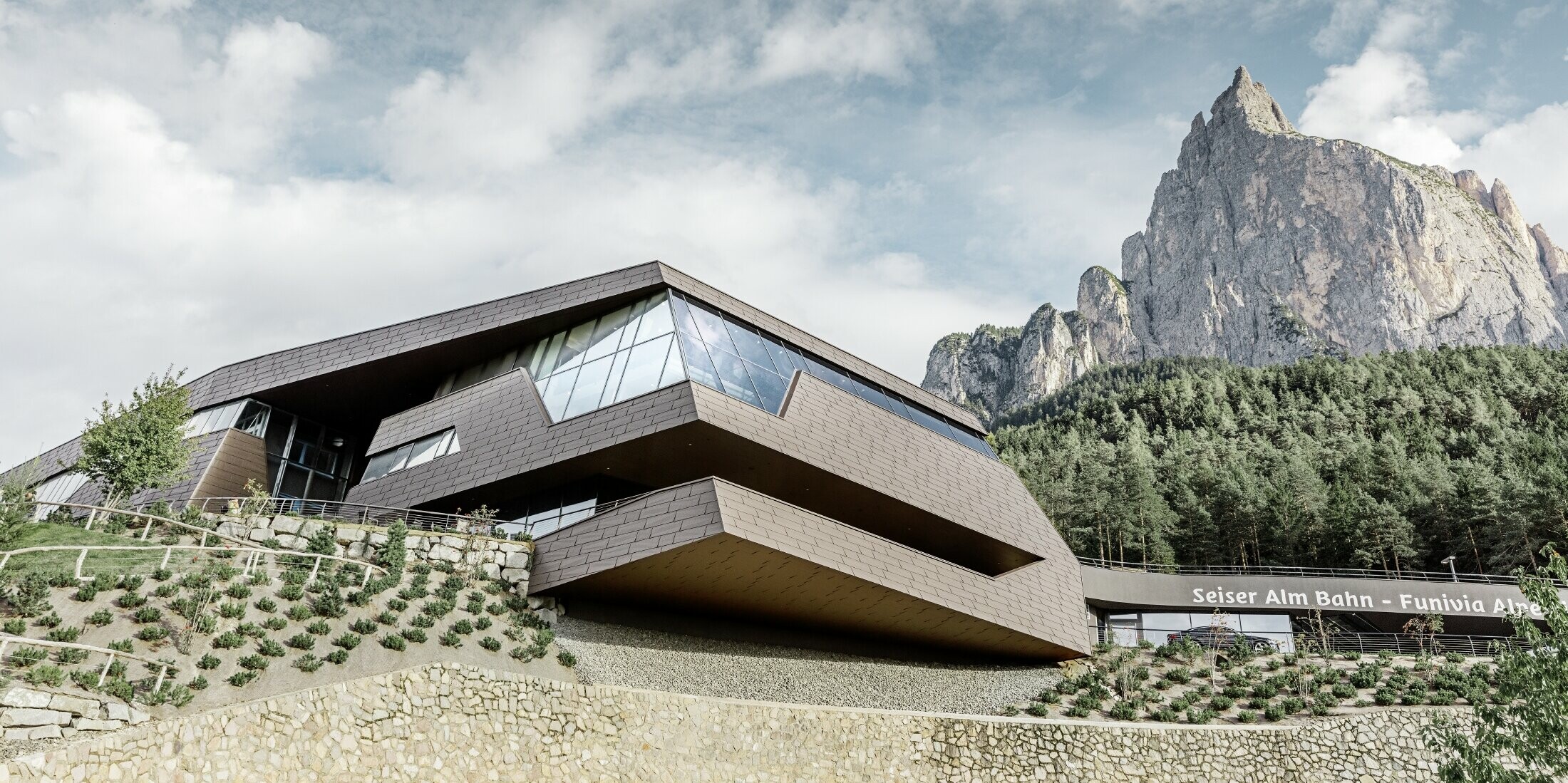 neu gestaltete Talstation der Umlaufbahn Seiser Alm, ähnlich der Dolomiten im Hintergrund mit unregelmäßigen Kanten und Oberflächen mit einer Aluminium Fassade in braun von PREFA