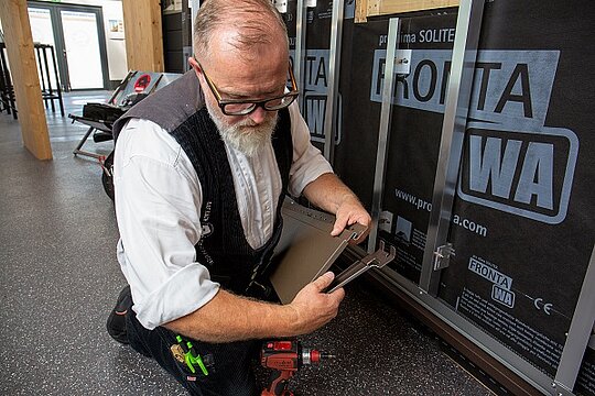 PREFA Techniker, Tom Weiß, demonstriert den Einbau der stirnseitigen Fuge. Die Fixierung erfolgt durch Umbiegen eine der oberen Laschen.