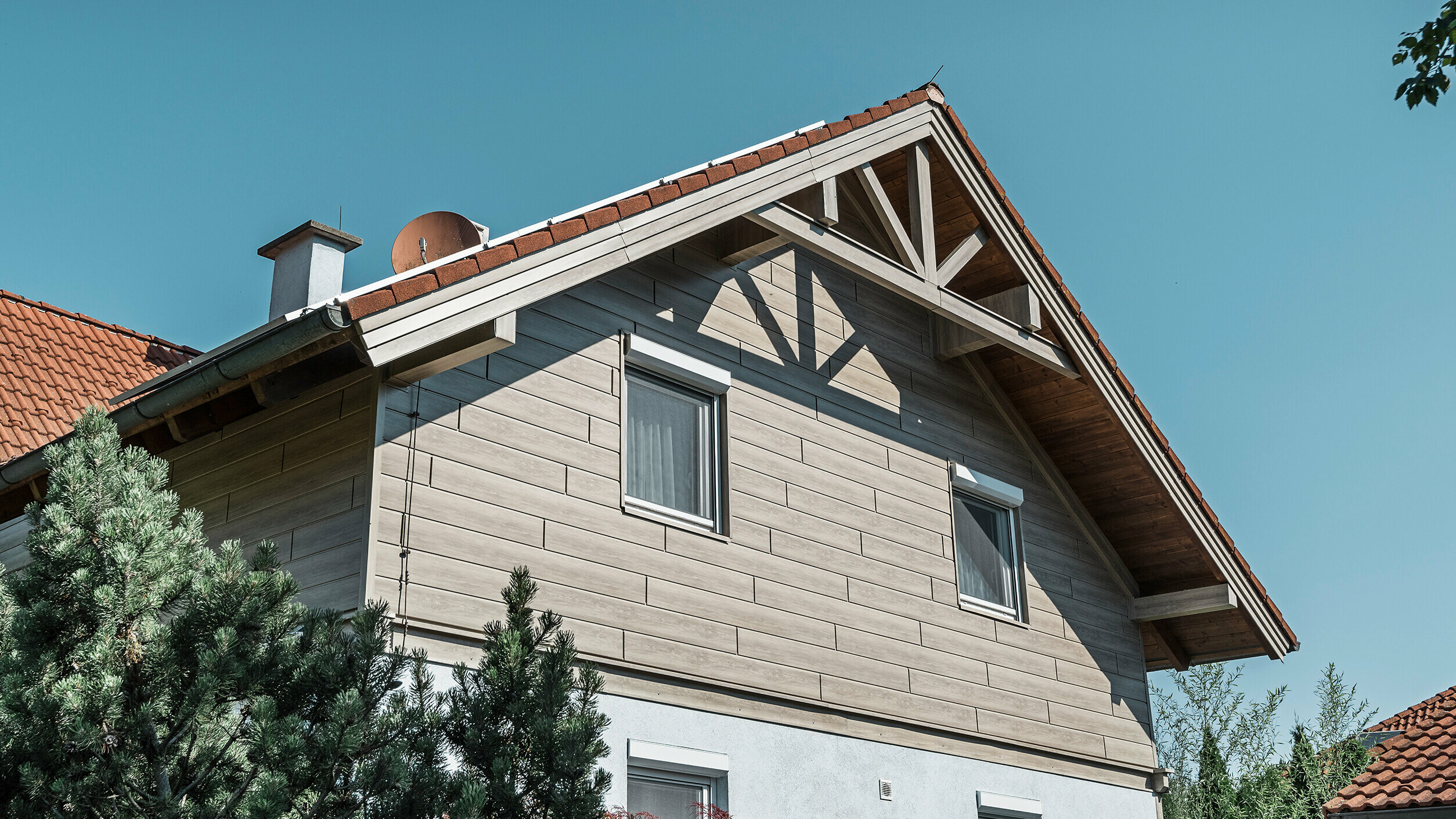 Einfamilienhaus in Landegg aus PREFA Sidings in Beige und Grau. Die verschiedenen Farbtöne der Sidings zeigen die Flexibilität bei der Farbgestaltung und verleihen dem Gebäude eine moderne und stilvolle Optik.