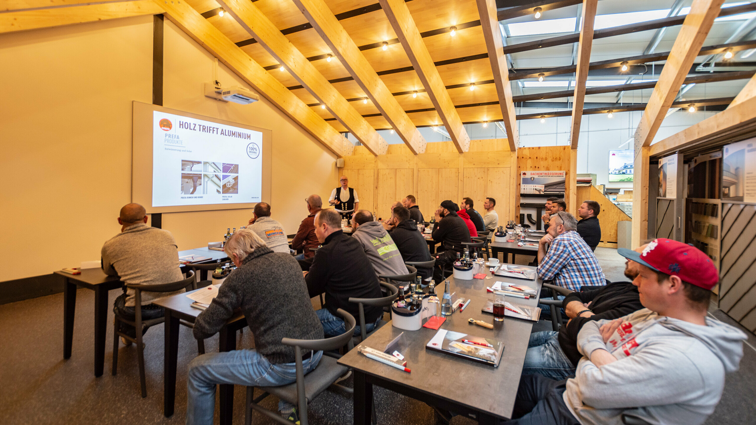 Ein voller Kurs in der PREFA-Academy in Neu-Ulm. Der Lehrverleger hält eine Präsentation. 