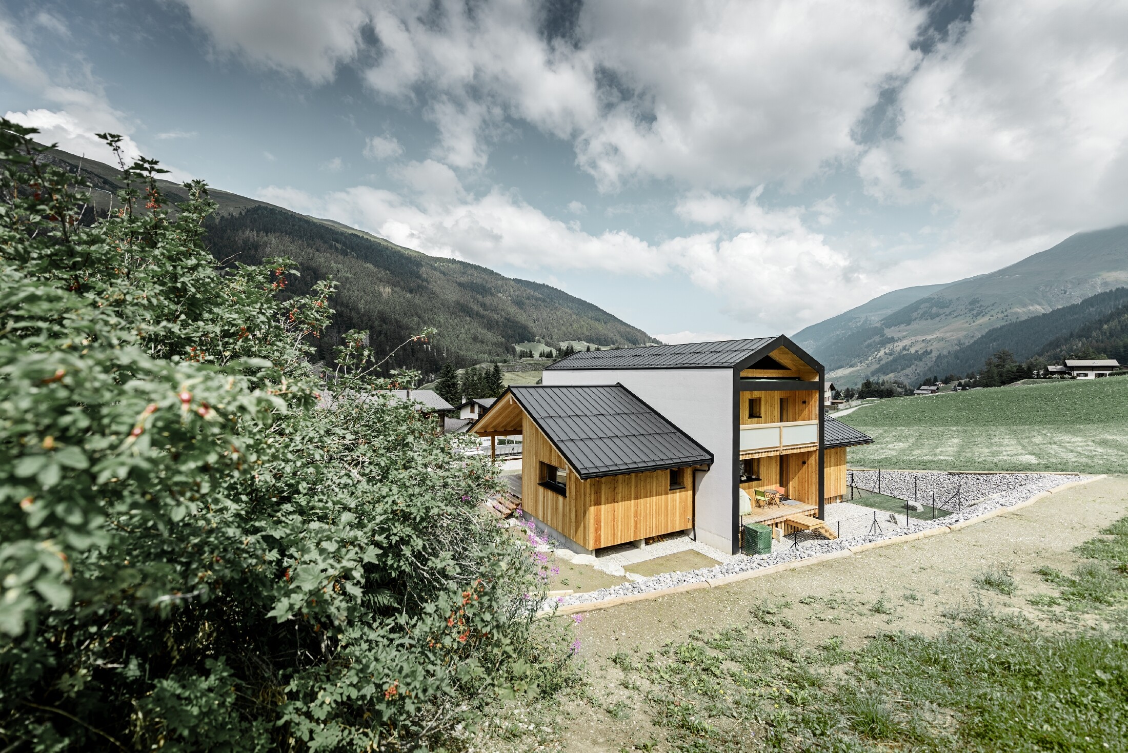 Dieses Einfamilienhaus wirkt, als wären 2 Häuser im 90° Winkel übereinander gestellt worden. Das Dach ist mit Prefalz in Schwarz und die Fassade zum Teil mit Holz verkleidet.