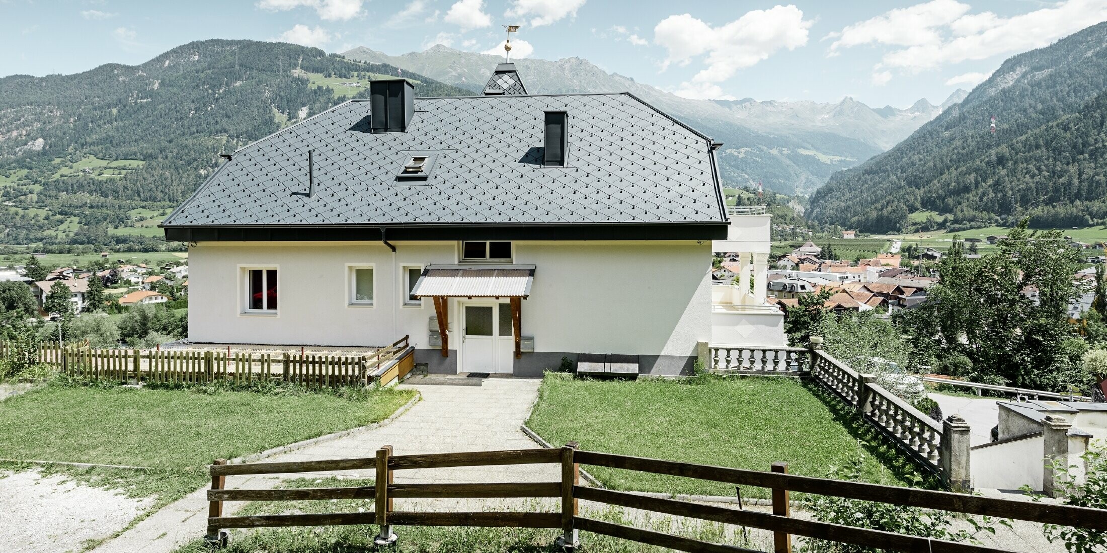 Felsenhaus mit Turm und einem Aluminiumdach in anthrazit mit einer Pizzeria im Erdgeschoss