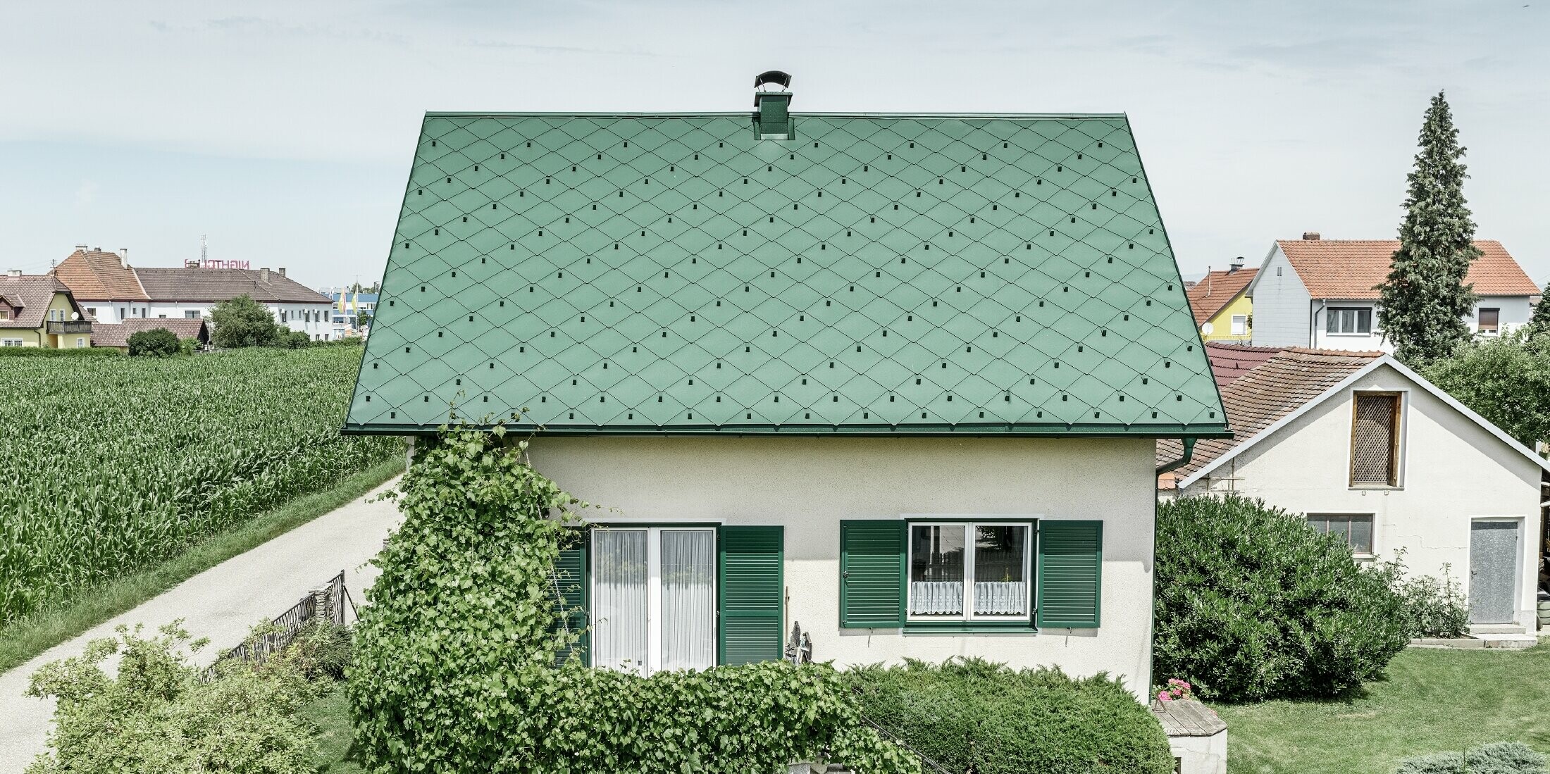 Klassisches Einfamilienhaus mit Satteldach mit einer Dacheindeckung aus Aluminium von in moosgrün mit grünen Fensterläden. Das Dach wurde mit PREFA Dachrauten 44 × 44 in P.10 Moosgrün eingedeckt.