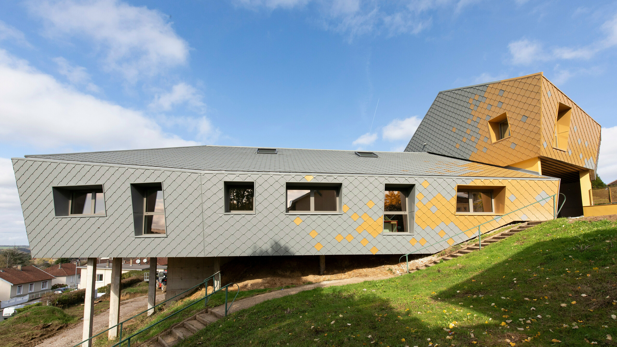 Seitliche Perspektive auf die PREFA Fassade der Grundschule Jean Peyraud in Pierre-Buffière in Hanglage