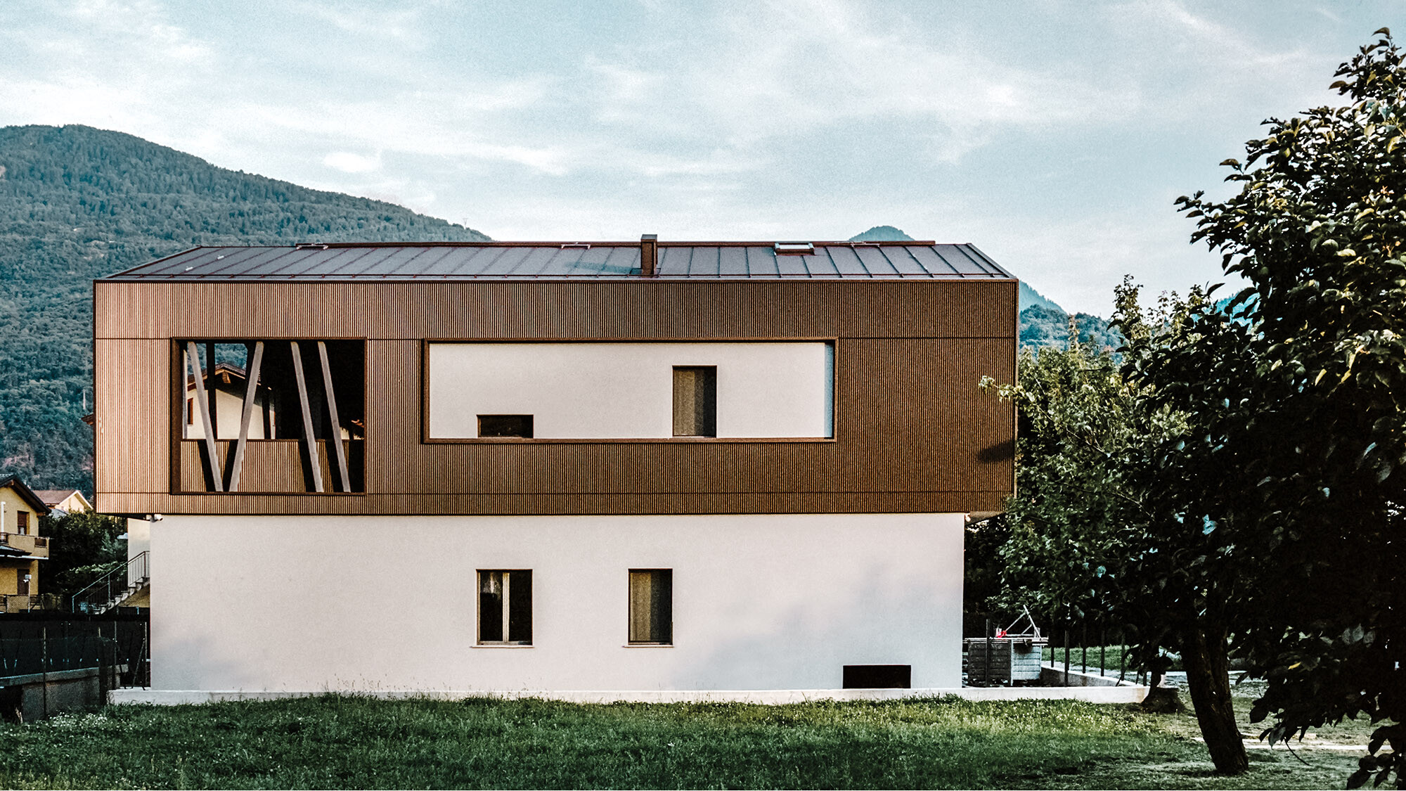 Die Villa 2B von der Seite; ihre Aluminiumhülle sieht aus, als wäre sie über die Putzfassade gestülpt.