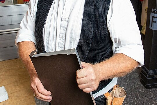 Der PREFA Techniker hält die selbst erstelle Fensterbank mit wasserdichter Quetschfalte in der Hand.