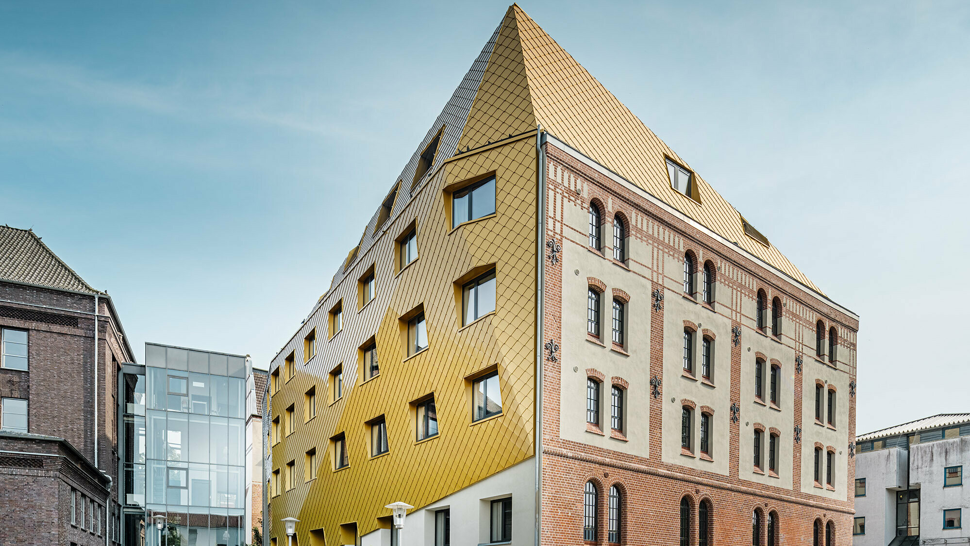 Das Studentenwohnheim aus der Froschperspektive: Die historische Fassade erstreckt sich rechts, die neue PREFA Hülle stülpt sich links bis über das Dachgeschoss.