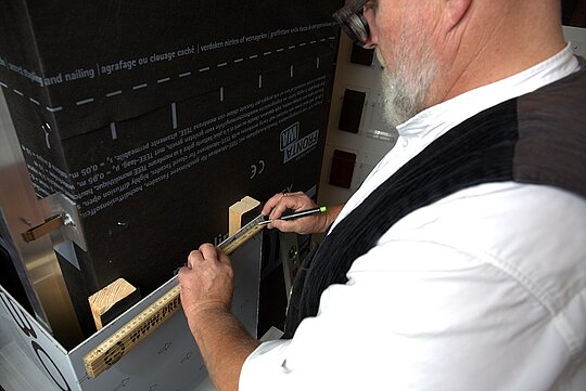 Tom Weiß reißt Löcher für die spätere Bohrung auf einer PREFA Verbundplatte an.