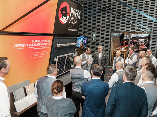 Das PREFA Team wird auf der BAU Messe vom technischen Leiter der PREFA Deutschland zum neuen PREVARIO 3.S Solarmontagesystem gebrieft. Im Fokus stehen innovative Lösungen für Dach und Solar, mit einer Infotafel über das System sowie einem ausgestellten Solarmodul.