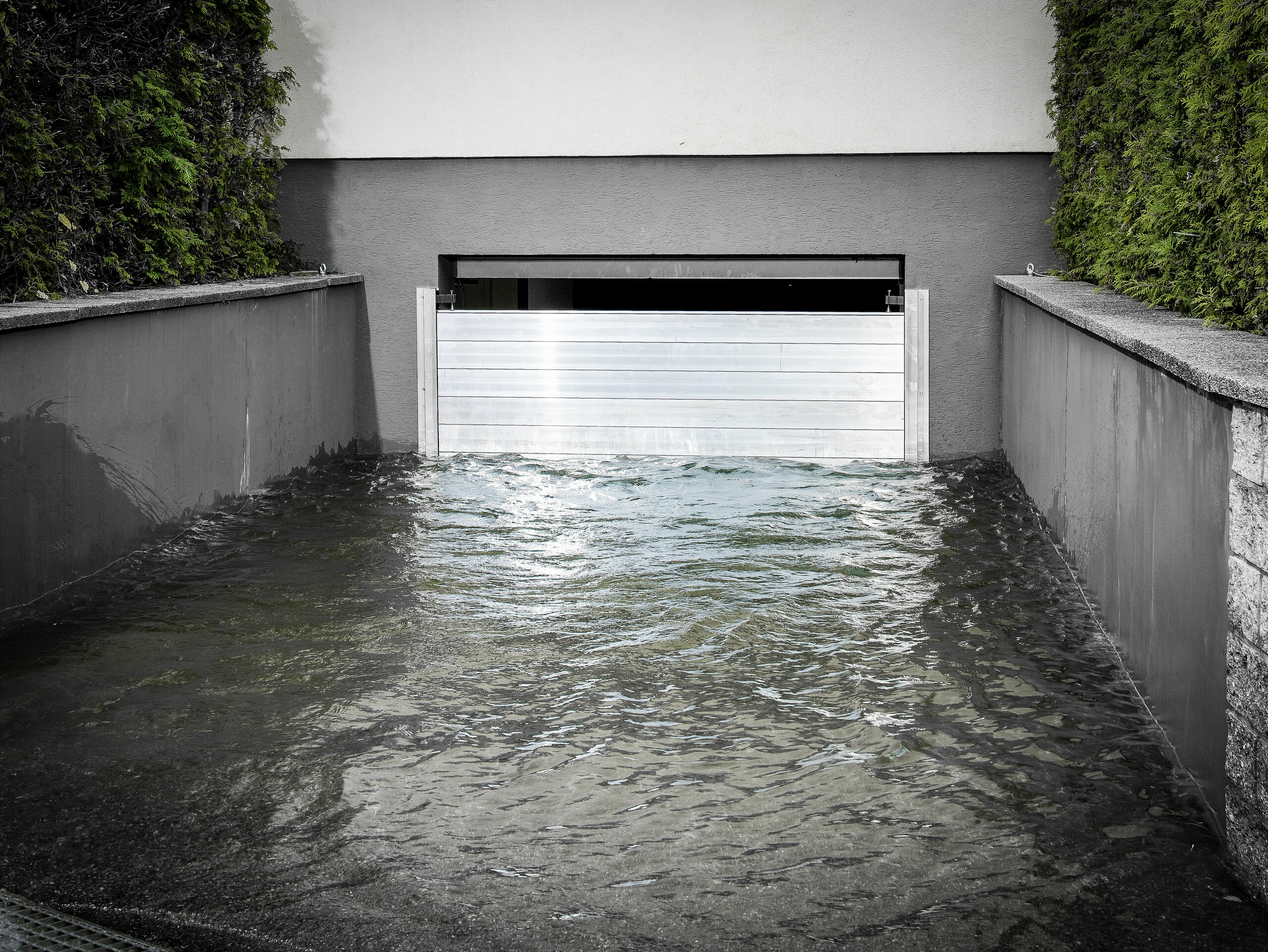 Auf dem Bild ist eine montierte Hochwasserschutzwand zu sehen, das eine Garage vor großen Wassermengen schützt.