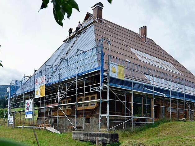 Foto der Baustelle am denkmalgeschützten Fusenhof mit zum Teil neu eingedeckten Dach mit der Aluminiumraute 44x44 von PREFA in steingrau