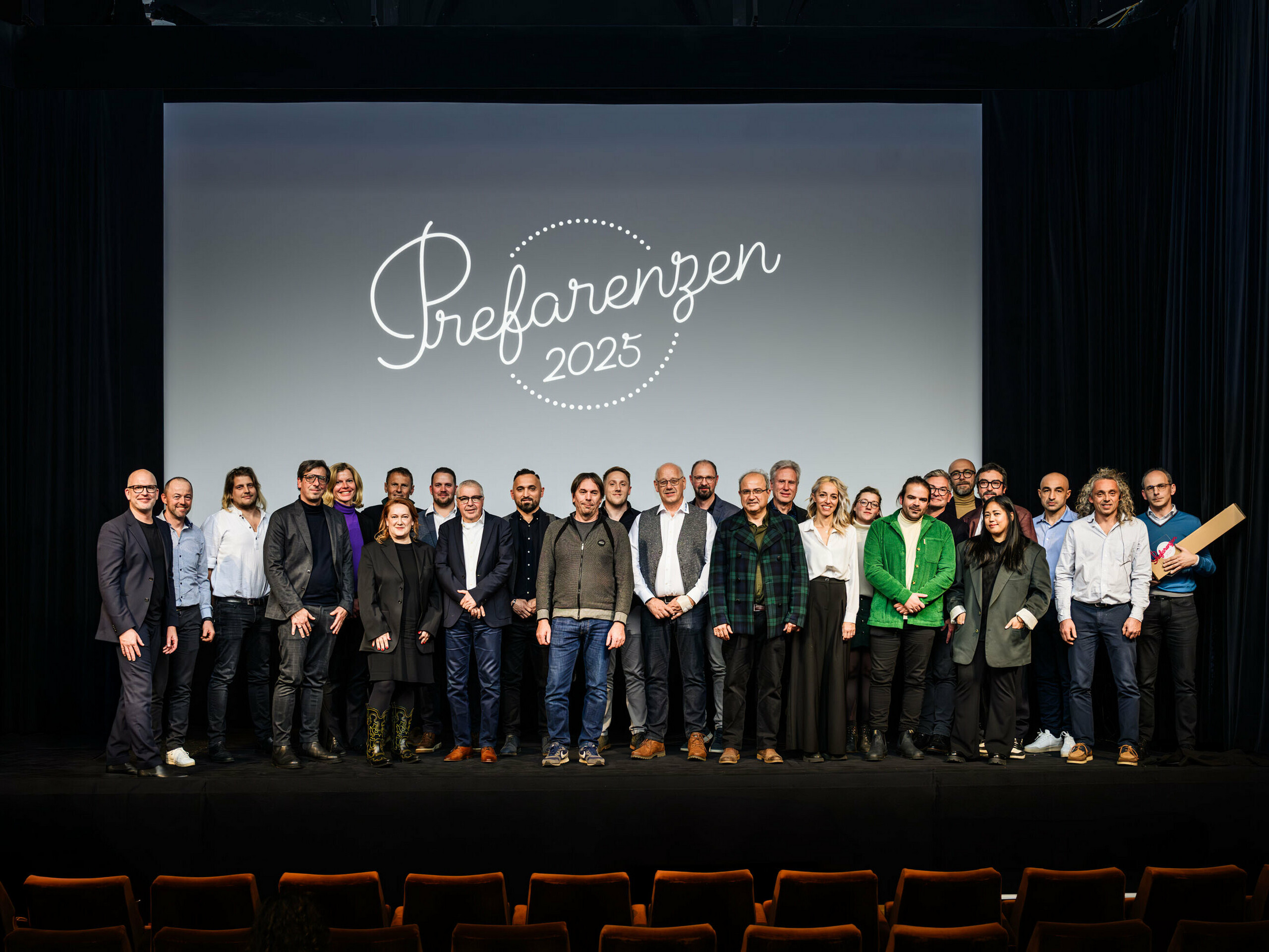 Gruppenfoto bei der PREFARENZEN-Premiere 2025 im Stadtkino Wien: Jürgen Jungmair, Marketingleiter von PREFA, mit den Mitwirkenden und Gästen vor dem Logo der Veranstaltung ‚Prefarenzen 2025‘ auf der Leinwand. Die Teilnehmer:innen repräsentieren Architektur, Planung, Verarbeitung und Medien aus ganz Europa.