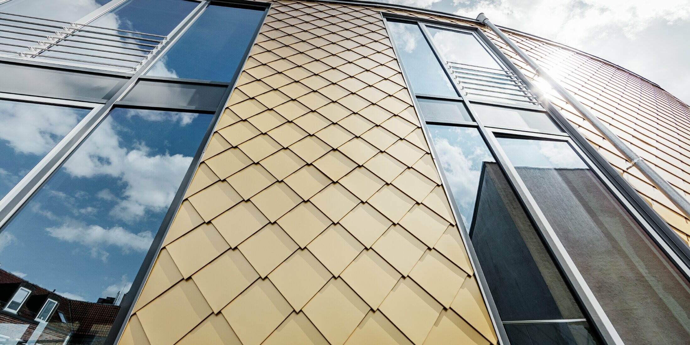 Goldene Alu-Raute von PREFA in Mayagold; große Glasflächen an der Fassade des Geschäftshauses;