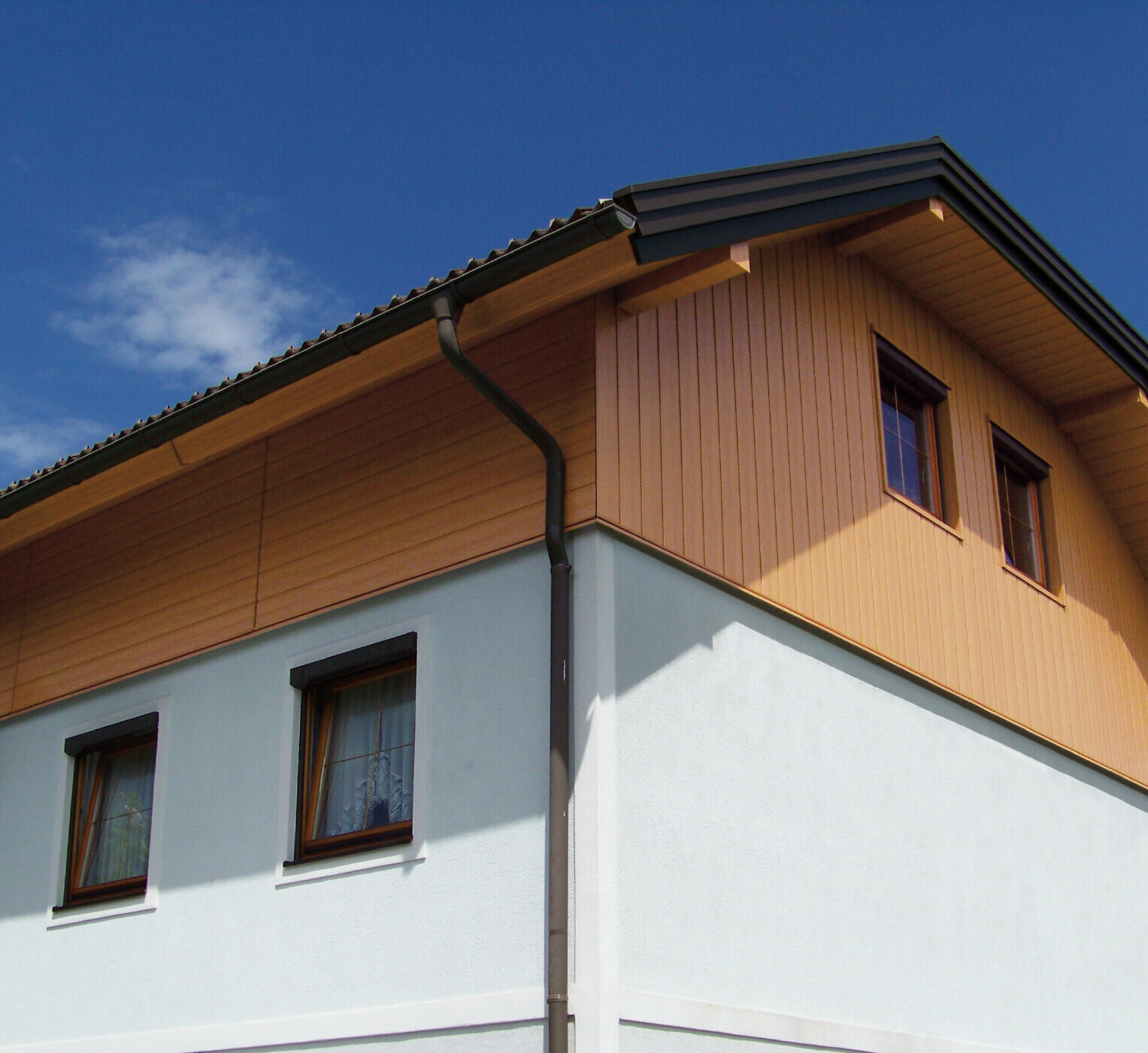 Großes Einfamilienhaus mit Krüppelwalmdach und einer Giebelverkleigung mit den PREFA Sidings in Holzoptik (Farbe Eiche natur)