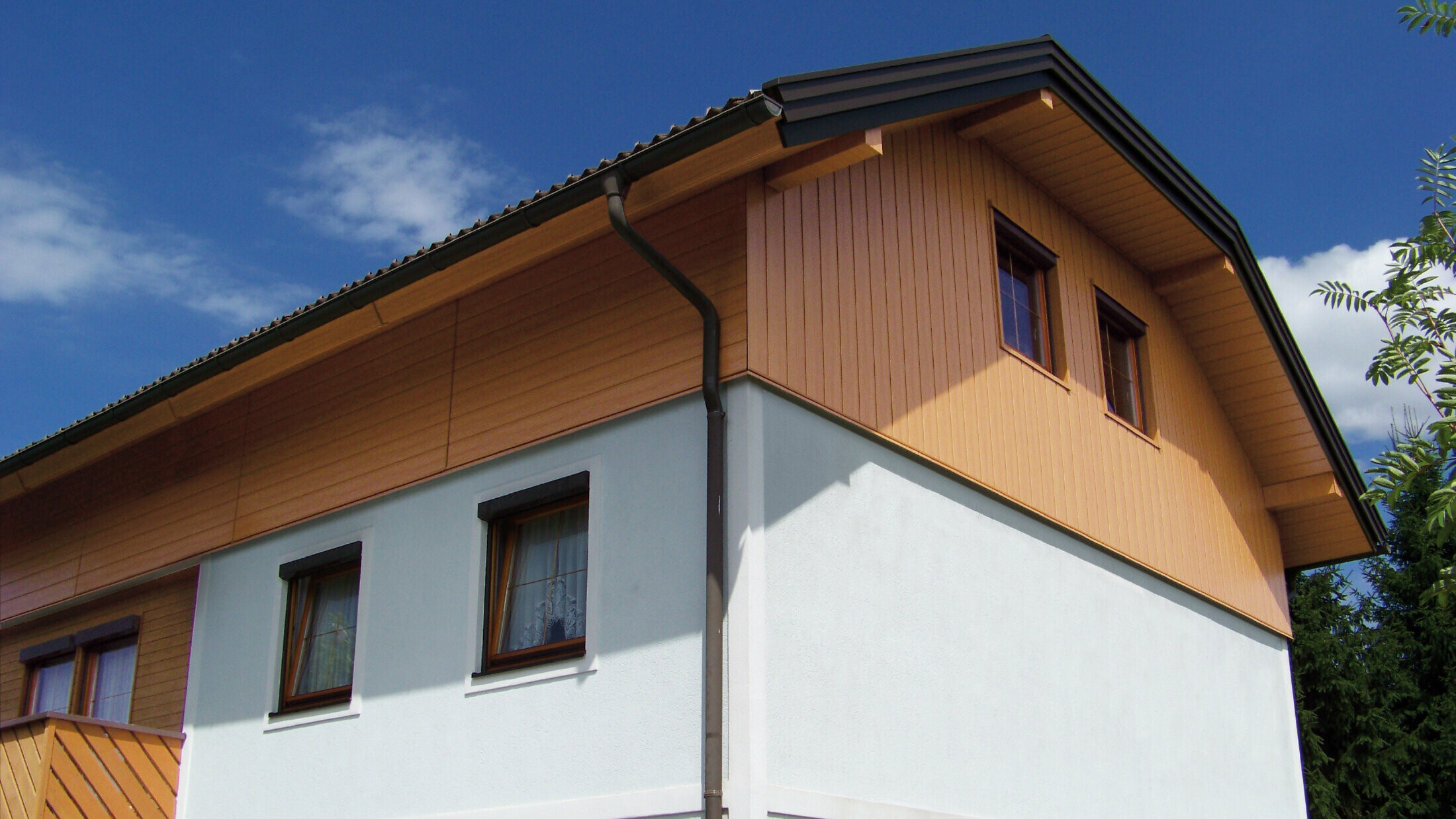 Großes Einfamilienhaus mit Krüppelwalmdach und einer Giebelverkleigung mit den PREFA Sidings in Holzoptik (Farbe Eiche natur)